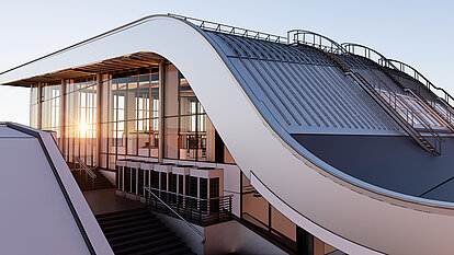 Modernes Gebäude mit geschwungener Dachform und Glasfassade im Licht des Sonnenuntergangs. Eine Treppe mit Geländer führt zum Eingang.